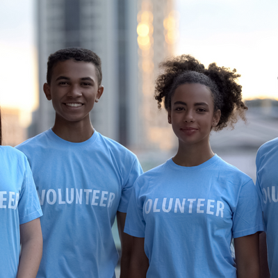 Two smiling teenagers wearing shirts that read "volunteer"